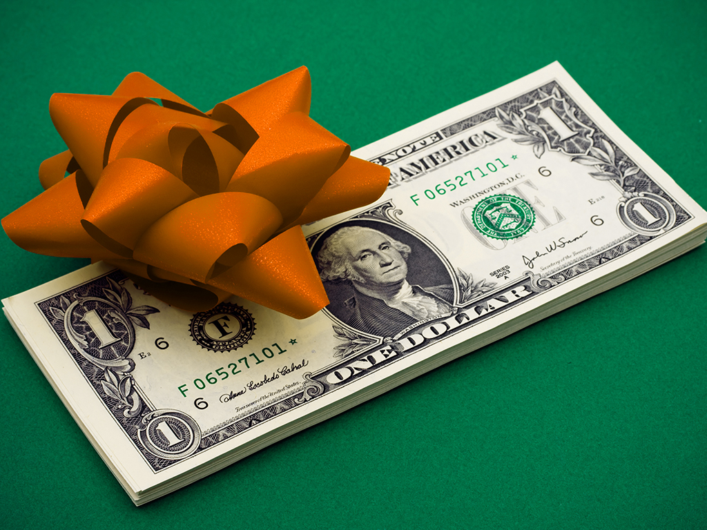 a stack of dollar bills with orange gift bow on top, set against a green background. Symbolizing the gift of money.
