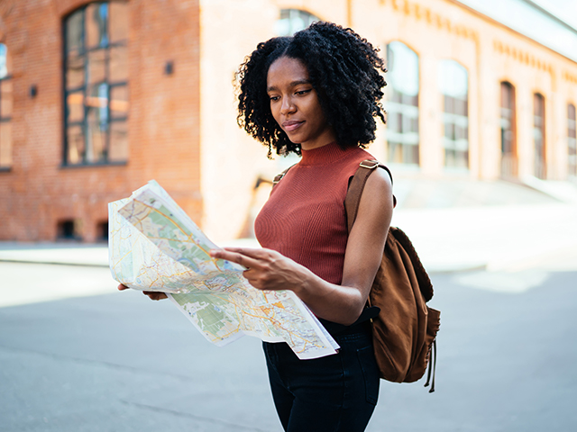 young adult female focused holding map exploring town
