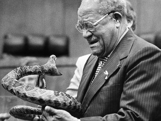 Joe Lang Kershaw, with tears in his eyes, receives a special gift from his fellow House members during a recognition ceremony on the House floor in 1981: a stuffed rattlesnake, the mascot of his Alma Mater, Florida A&M University. His colleagues are honoring him for his dedicated years of service since 1968. - Photographed on May 8, 1981. by Foley, Mark T.