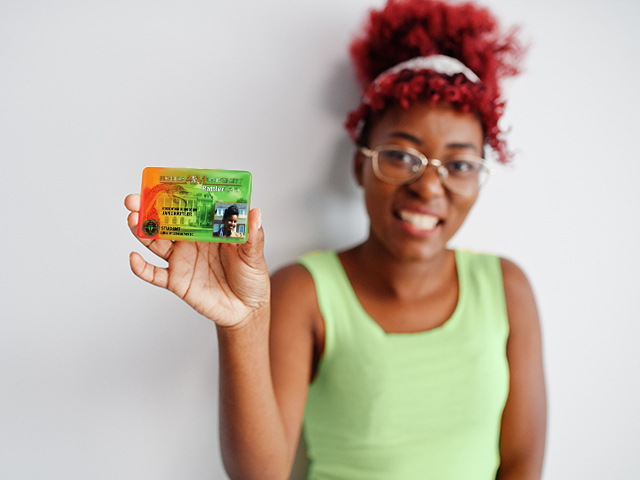A young woman student proudly displaying her colorful orange and green student ID card.