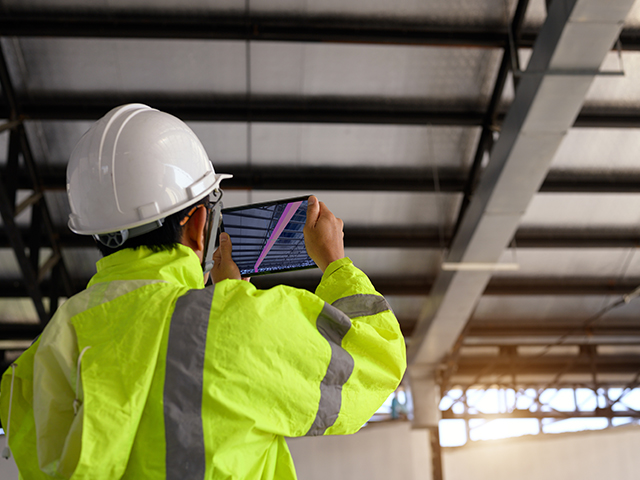 A civil engineer doing a construction inspection by using a tablet to scan building