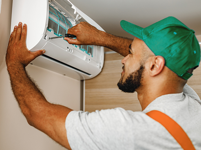 Professional repairman installing air conditioner in a room