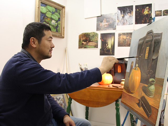 Nan Liu painting in his studio at railroad square art park