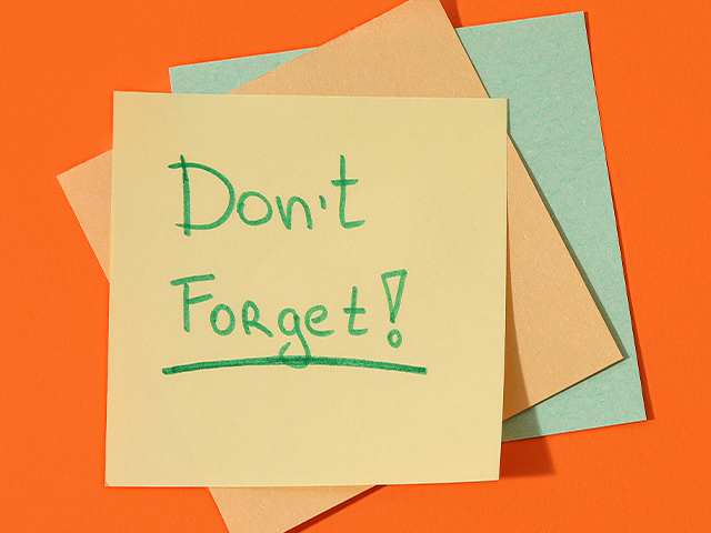 A stack of sticky notes, The top one reads "Dont Forget" written in green marker 