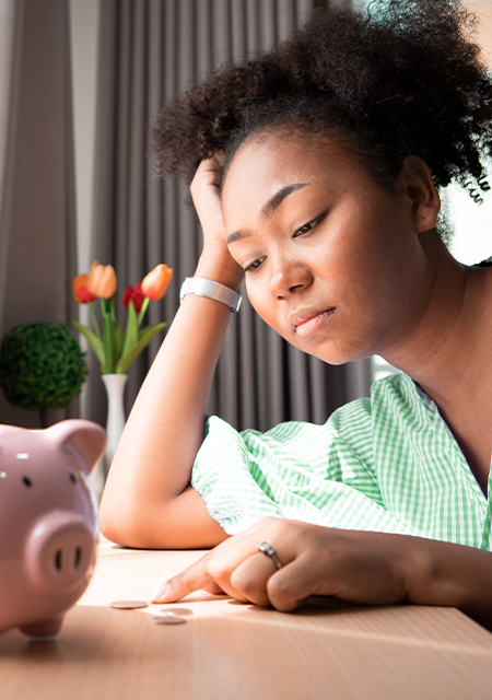 Helping to Prepare for the Future An upset young woman counts coins infront of a piggy bank