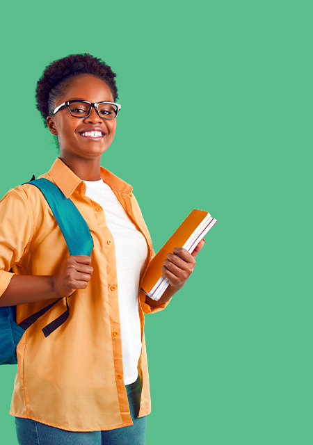 Young smiling African American female student in an orange shirt holding a small stack of books, standing in front of a green background