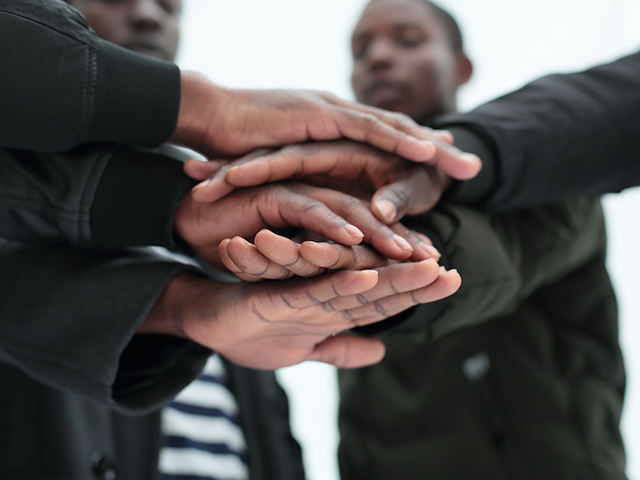 Group of african american young men standing in circle and stacking their hands in a circle