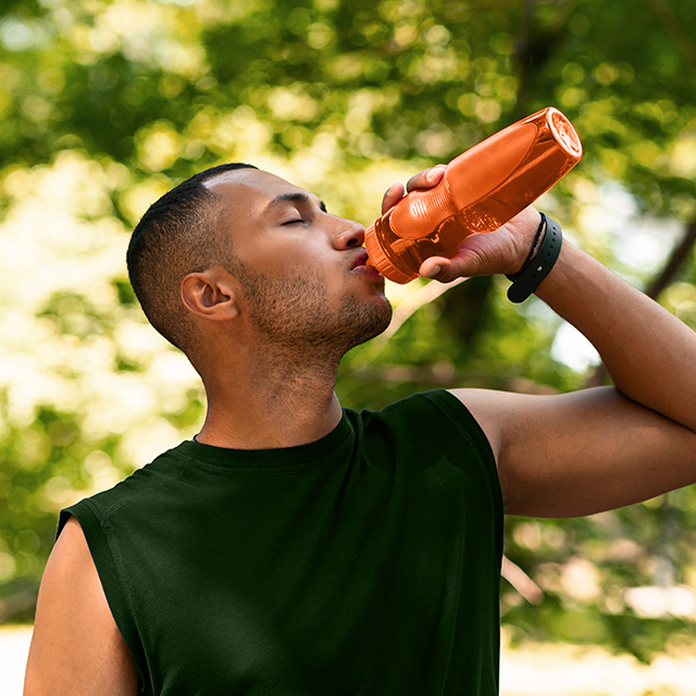 A man drinking water from an orange water bottle