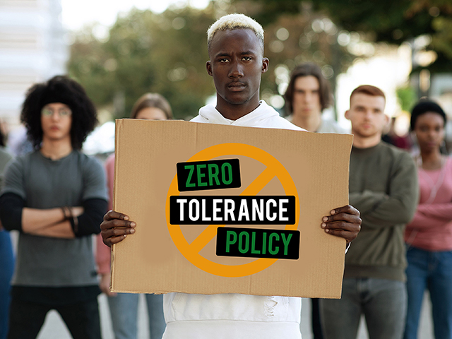 Young man holding sign that says "Zero Tolerance Policy" 