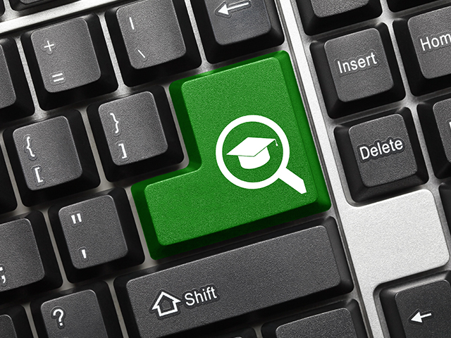  Close-up of a black keyboard featuring a green enter key with a graduation cap icon